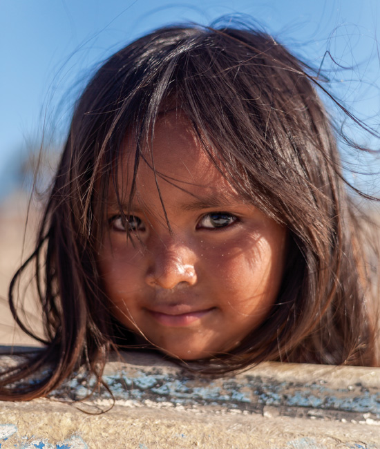 David Paniagua / Una niña seri recarga su rostro de cobre sobre un bote varado en la playa. 