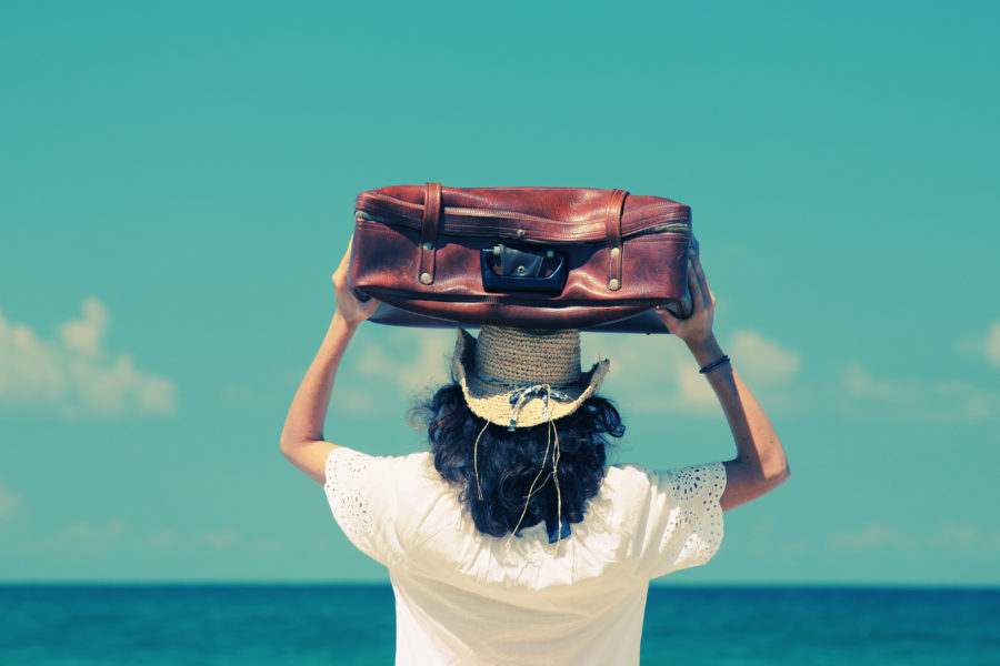 woman with suitcase on the beach